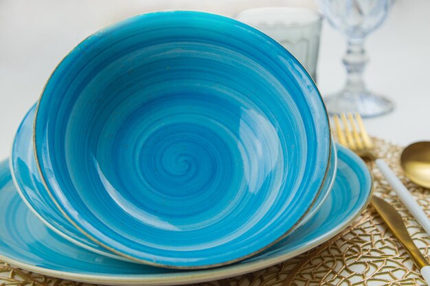 Bright blue serving plates with a spiral pattern tilted one after the other serving devices of gold