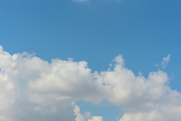 Bright blue sky with white clouds and a flying plane Travel concept