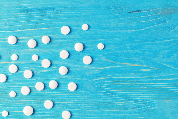 こぼれた白い錠剤と明るい青い木製の背景
