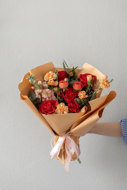 A bright bouquet of flowers in beige packaging Red roses Mattiol Ranunkulus bush cloves