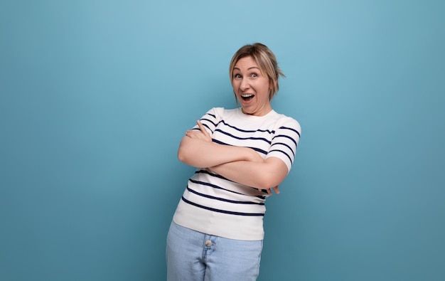 Of a bright cheerful blonde woman in a casual outfit laughing enthusiastically on a blue background