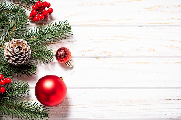 白い素朴な背景にモミの木の枝と赤いボールと明るいクリスマスバナー