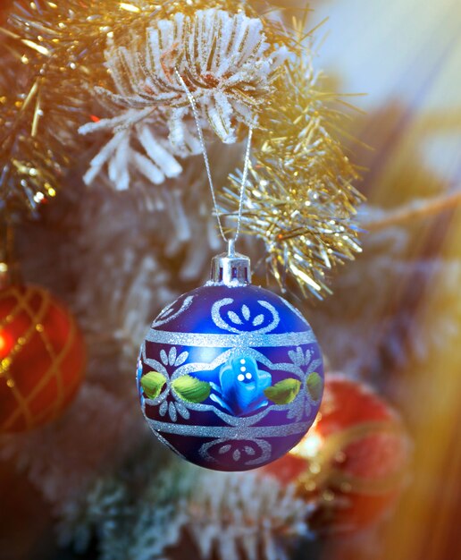 Bright Christmas bauble from a snow covered Christmas Tree Branch