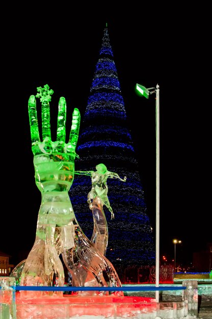 Bright Christmas tree in bright lights against the background of ice sculptures