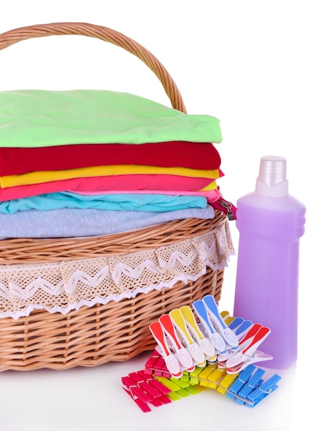 洗濯かごの中の明るい服、ピン、洗濯用シャンプー付きボトル、白で隔離
