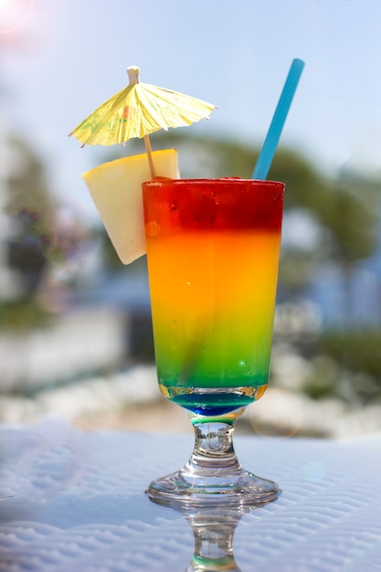 Bright cocktail with umbrella on the background of the pool