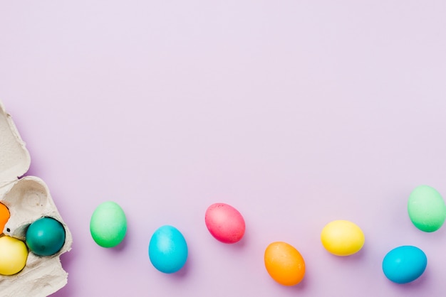 Photo bright collection of row of colored eggs near container