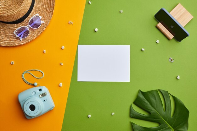 Bright color pop composition of blank white paper and instant camera over graphic tropical background with vacation vibes , 