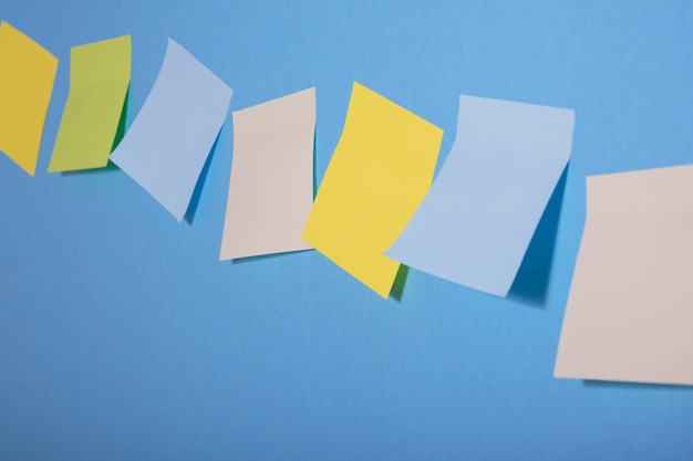 Bright colored sticky notes on blue background in a row, selective focus