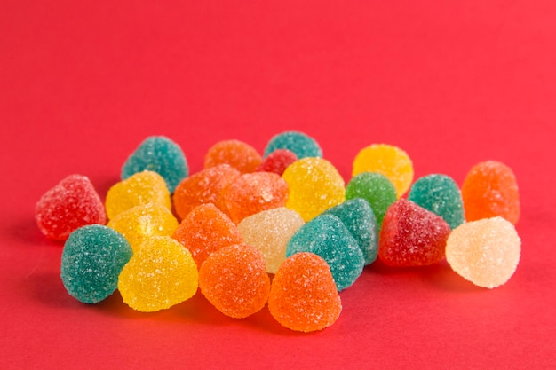 Bright colorful jelly candies in sugar on bright red background