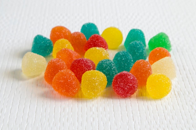 Bright colorful jelly candies in sugar on white textured background