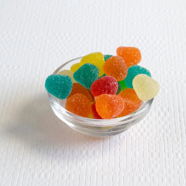 Bright colorful jelly candies in sugar on white textured background