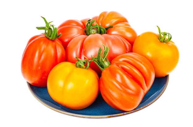 Bright colorful tomatoes on plate isolated on white background. 