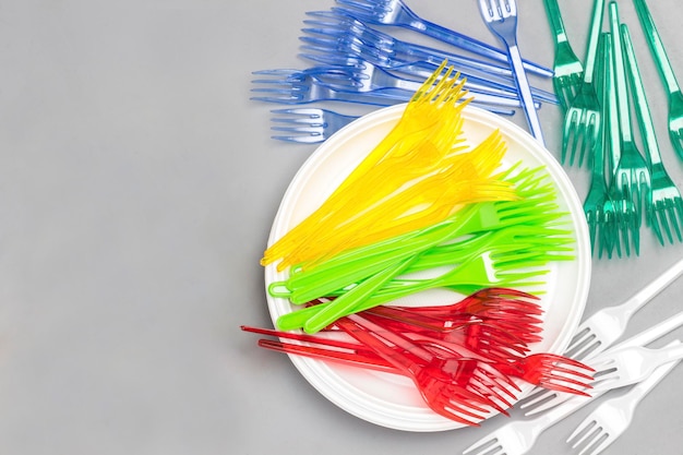 Foto vaste di plastica dai colori vivaci forchette di plastica cannucce su piatto bicchieri di carta colorati