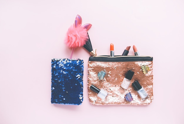 Bright composition of fashion accessories. Glitter sequins cosmetic bag and decorative tinsel. Object on soft pastel background. Flat lay, top view.