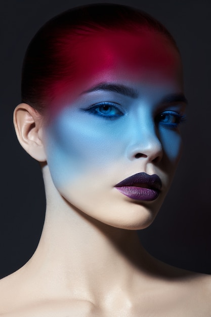 Bright contrasting beauty makeup portrait of a woman in blue and red shadow tones.