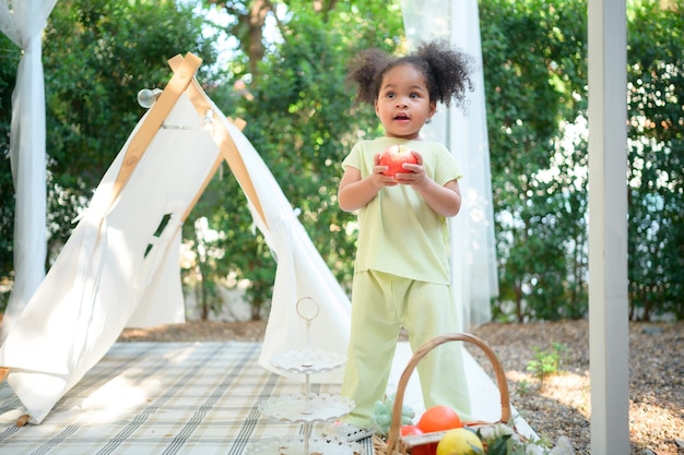 A bright and cute little girl with fun playing in the garden of the house