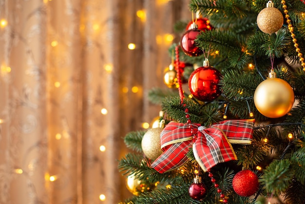 Albero di natale decorato luminoso foto del primo piano di un albero di natale decorato con un fiocco rosso e palline dorate con spazio per la copia