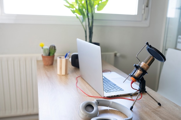 Bright desk with computer microphone and headphones on the table