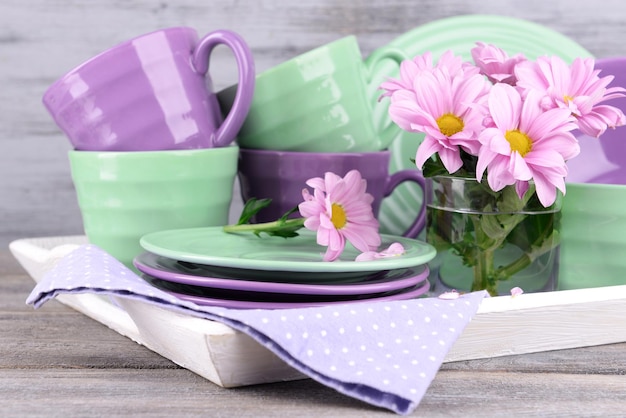 Bright dishes with flowers on wooden background