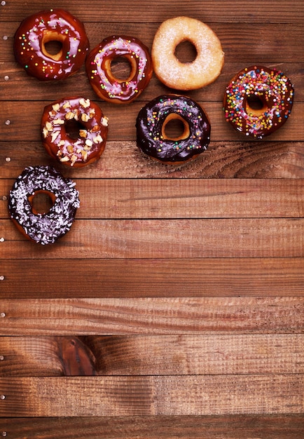 Bright donuts on wooden background.