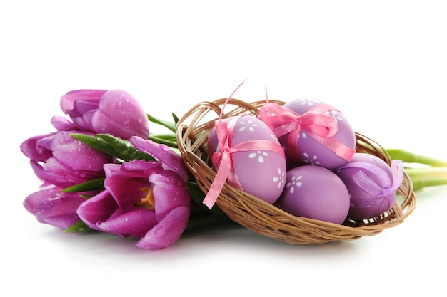 Bright easter eggs in basket and tulips isolated on white