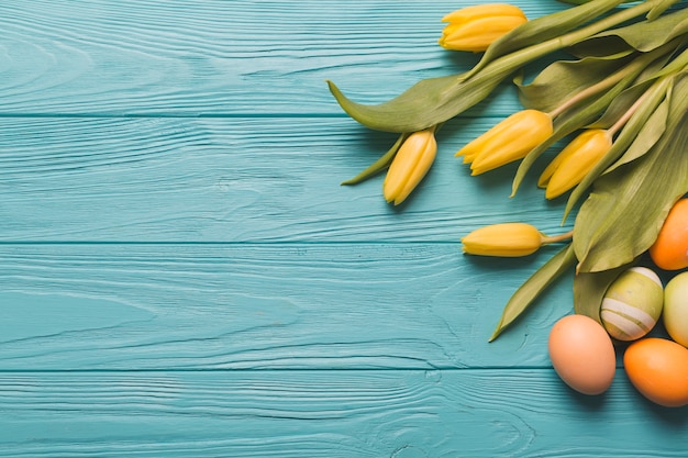 Bright eggs and tulips on turquoise background