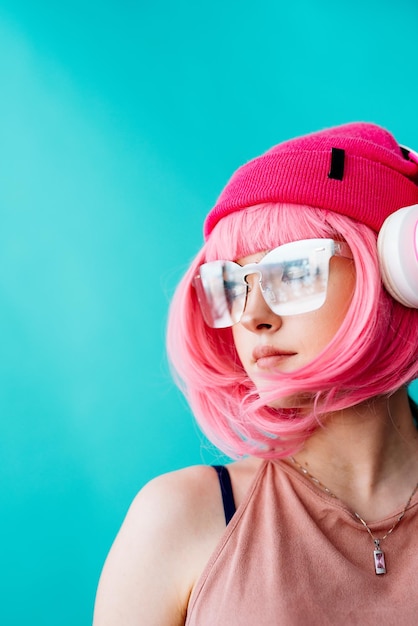 Foto ritratto di un'apparenza brillante e stravagante di una ragazza con un corto taglio di capelli rosa su uno sfondo blu