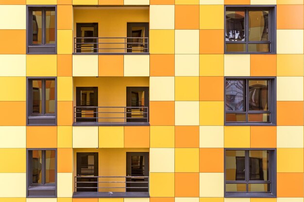 Фото Яркий фасад жилого дома в желтых тонах, с окнами, балконами и дверями