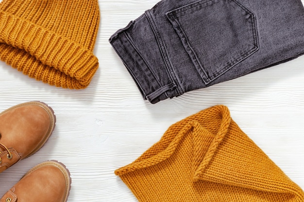 Яркая модная одежда Вязаный шарф и кепка оранжевого цвета удобные кожаные туфли и черные джинсы