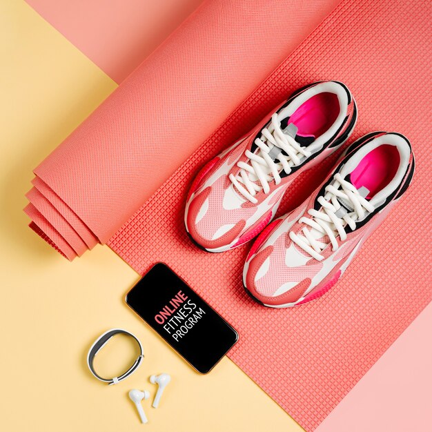 Bright fashion sneakers met smartphone, fitnessarmband en roze yogamat. App om binnen te trainen. Online fitnessprogramma. Thuis online training.