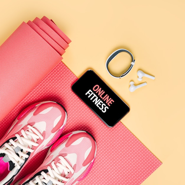 Bright fashion sneakers met smartphone, fitnessarmband en roze yogamat. App om binnen te trainen. Online fitnessprogramma. Thuis online training.