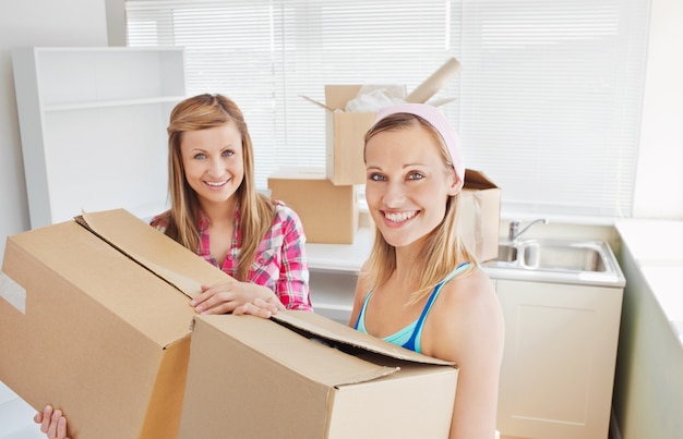 Bright female friends holding boxes 