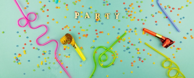 Photo bright festive party background - cocktail straws and party whistles with scattered sugar sprinkles.