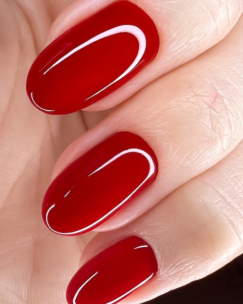 Bright festive red manicure on female hands nails design