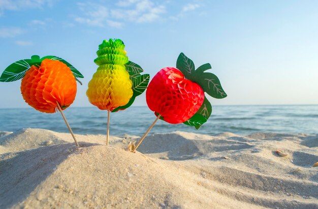 Bright figure colored paper decorations for cocktail on sandy sea beach