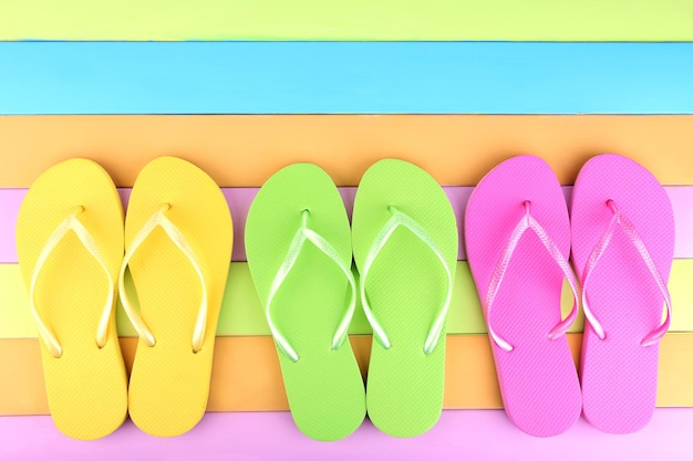 Photo bright flipflops on color wooden background
