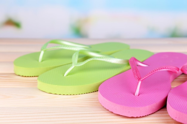 Bright flipflops on wooden table on nature background