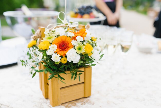 Bright floral arrangement of white, yellow and orange chrysanthemum flowers in a wooden box