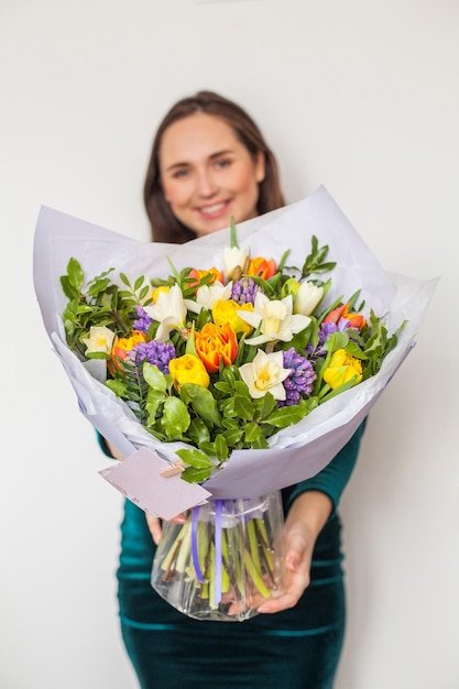 Bright flowers in female hand on white background