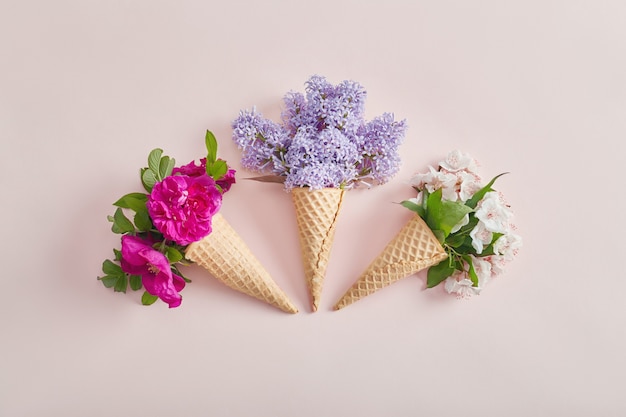 Bright flowers in a waffle cone on a pink paper background