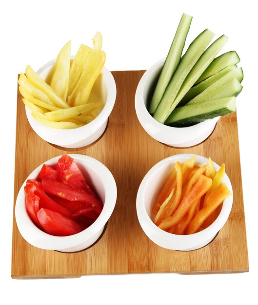 Bright fresh vegetables cut up slices in bowls isolated on white