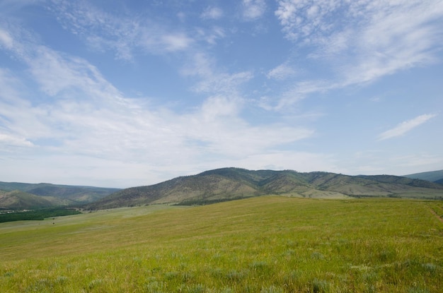 Prati verde brillante si estendono in lontananza fino alle montagne blu. il sole splende brillantemente