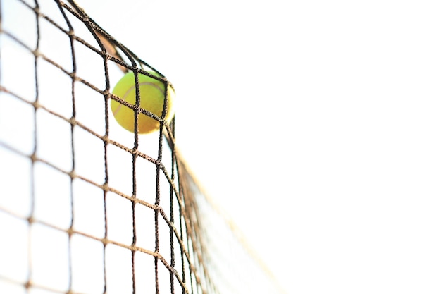 Ярко-зеленовато-желтый теннисный мяч попадает в сетку.
