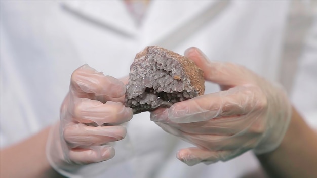 Bright grey ruby crystal ore in hands with gloves crystallization is the natural or artificial