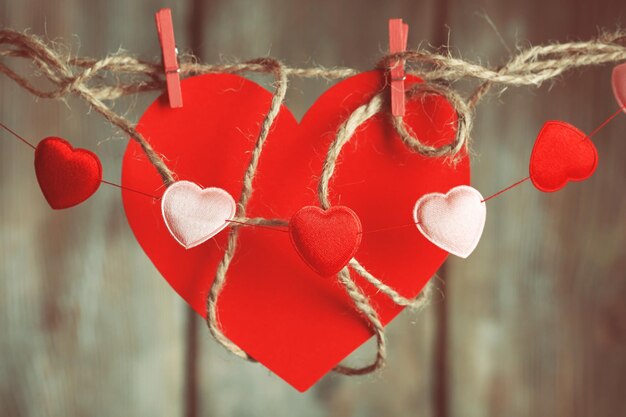 Bright hearts hanging on rope on wooden background