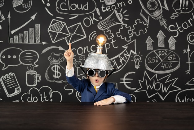 Bright idea! Funny child student in class against black chalkboard. Happy kid pretend to be businessman. Online education and e-learning concept. Back to school