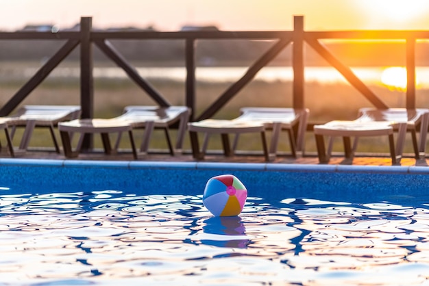 밝은 부풀릴 수 있는 여러 가지 빛깔의 공은 따뜻한 여름 태양 아래 푸른 맑은 수영장에서 깨끗하고 투명한 물 표면에 뜬다