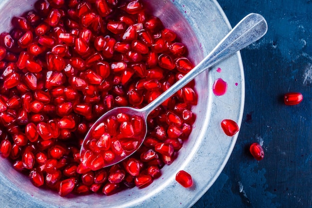 Bright juicy ripe pomegranate with seeds in a bowl on a dark background