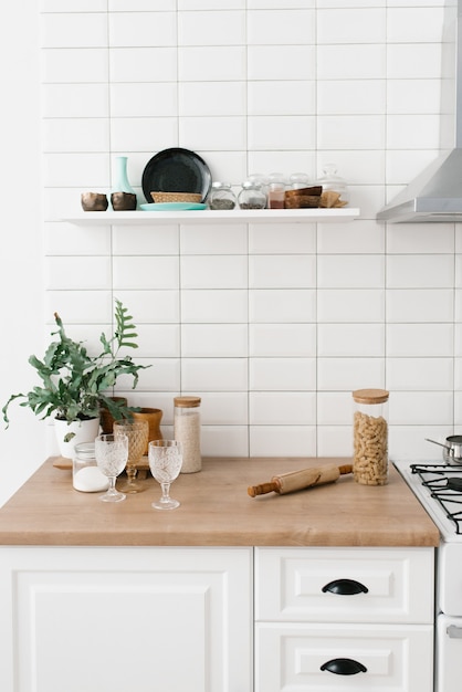 Bright kitchen in the Scandinavian style. Pasta in a glass jar, houseplant, glasses and kitchen utensils. Decor